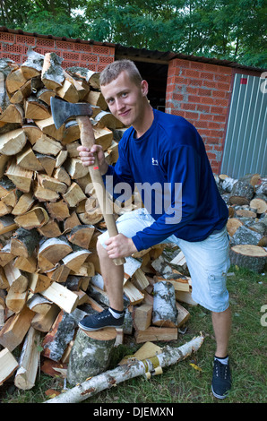 Il polacco teen legno azienda trinciatore ax accanto a gran mucchio di spaccare la legna. Zawady Polonia centrale Foto Stock