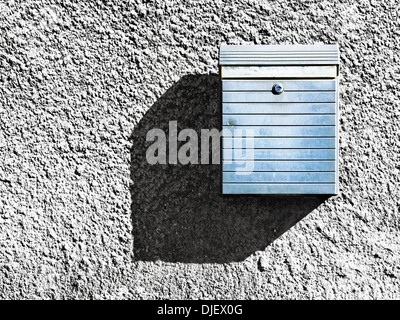 La cassetta postale a trama sulla parete di casa con ombra Foto Stock