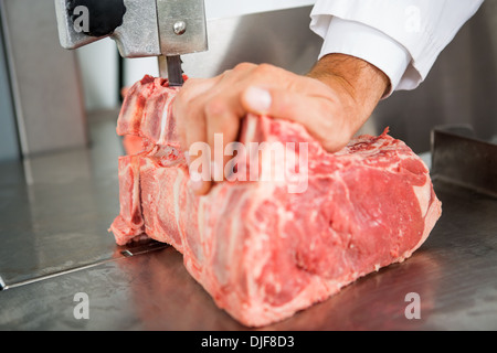 Mano il taglio di carne a fette sulla segatrice a nastro Foto Stock