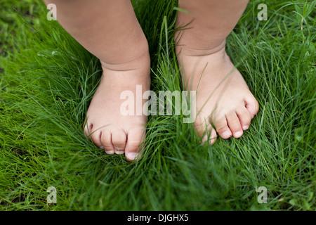 Piccoli piedi del bambino sull'erba verde. Foto Stock