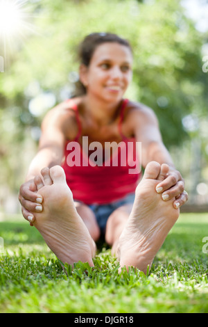 Sorridente giovane donna siede sull'erba. La faccia in defocalizzazione. Foto Stock