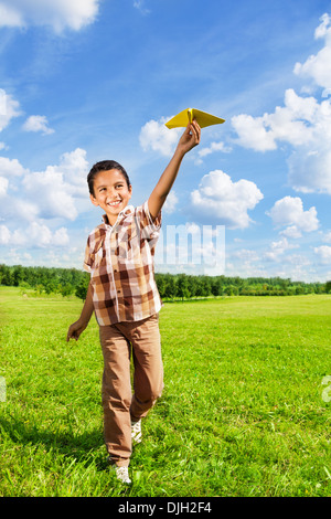 Felice ragazzo gettando aeroplano di carta in esecuzione nel parco sulla giornata di sole Foto Stock