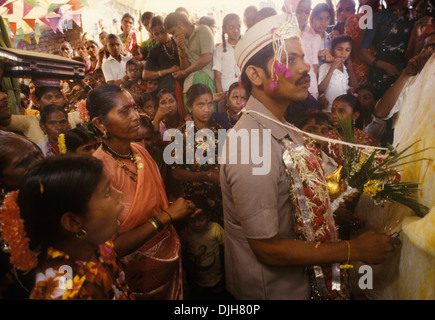Antarpat un panno bianco (R) tenuto tra la sposa e lo sposo, in modo che non possano vedersi al tradizionale matrimonio del villaggio indù. L'antarpat agisce come una cortina simbolica che separa la coppia prima dell'inizio dei voti matrimoniali. Lo sposo tiene una ghirlanda di fiori, che presenterà alla sua sposa come parte della cerimonia jaimala. La sua famiglia, gli ospiti del villaggio, le persone dietro di lui. Isola Elephanta chiamata anche Gharapuri, Mumbai, India. HOMER SYKES anni '1990 Foto Stock