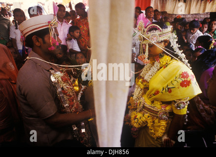 Tessuto bianco Antarpat tenuto tra la sposa e lo sposo, al tradizionale matrimonio del villaggio indù. L'antarpat agisce come una cortina simbolica che separa la coppia prima dell'inizio dei voti matrimoniali. Lo sposo tiene una ghirlanda di fiori, che presenterà alla sua sposa come parte della cerimonia jaimala. Isola Elephanta chiamata anche Gharapuri, Mumbai, India. HOMER SYKES anni '1990 Foto Stock