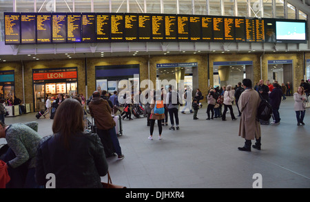 I passeggeri in attesa al di sotto della scheda di partenze presso la stazione di Kings Cross Londra Foto Stock