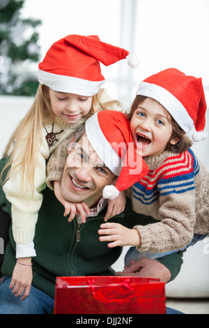 Padre Piggybacking i bambini durante il periodo di Natale Foto Stock