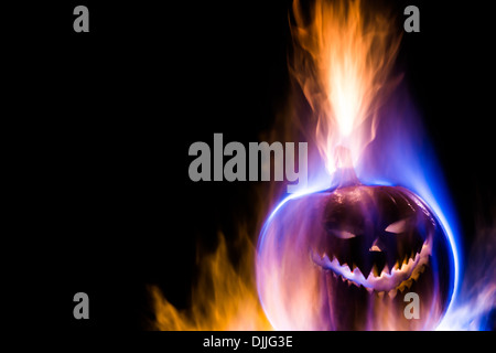 Un jack-o-lantern zucca circondato da blu, arancione e viola fiamme, isolati su nero con copia spazio. Foto Stock