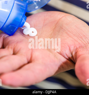 Donna matura schiacciamento skincare crema di sua mano, close up Foto Stock