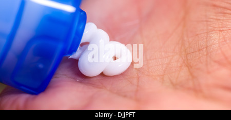 Donna matura schiacciamento skincare crema di sua mano, extreme close up Foto Stock