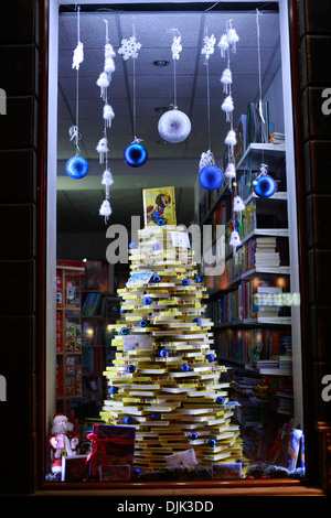 Splendidamente decorate Natale bookstore finestra, la visualizzazione di fatto a mano albero di Natale fatto di libri. Foto Stock