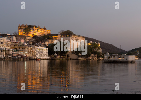 Vista della città di Udaipur in serata con lago Pichola e il palazzo della città sfondo illuminato Foto Stock