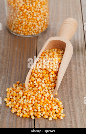 Essiccato di chicchi di mais in legno da scoop su uno sfondo di legno Foto Stock