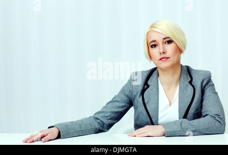Ritratto di un giovane pensieroso donna seduta al tavolo in ufficio Foto Stock