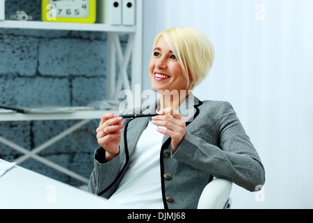 Felice imprenditrice rilassante sul suo posto di lavoro in ufficio Foto Stock