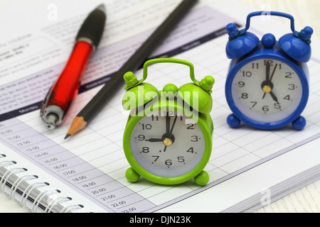 Orologi in miniatura che mostra 9 am e 5 pm su agenda aperta Foto Stock