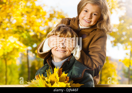 Ritratto di bimba bionda nascondi ragazzi occhio con indovina chi sorpresa in autunno park Foto Stock