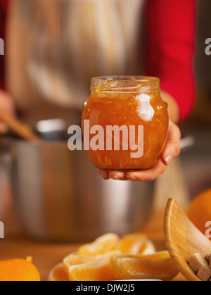 Primo piano sul giovane casalinga che mostra orange jam Foto Stock