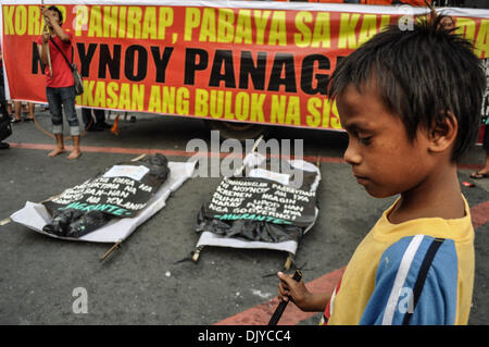 Manila, Filippine. 30 Novembre, 2013. Un bambino lampeggia come due mock-up body bags sono stabilite nella parte anteriore del palco, raffigurante il body bags sparse all'typhoon aree devastate. I gruppi militanti mark patriota filippino, Andres Bonifacio il 150° compleanno, tenendo le proteste e le varie attività di Manila, sabato, 30 novembre 2013. Citando che il presidente avrebbe guadagnato Bonifacio ire, la protesta è guidata dal diritto del lavoro nazionale centro Kilusang Mayo Onu (KMU), coincidente con altri gruppi di lavoro' proteste in tutto il paese.Foto: George Calvelo/NurPhoto (credito Immagine: © George Calvelo/NurPh Foto Stock