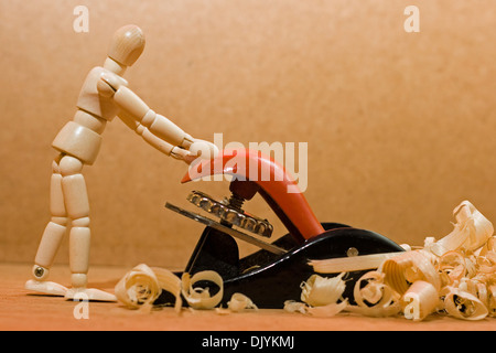 Manichino uomo spingendo un piano per la lavorazione del legno. Foto Stock