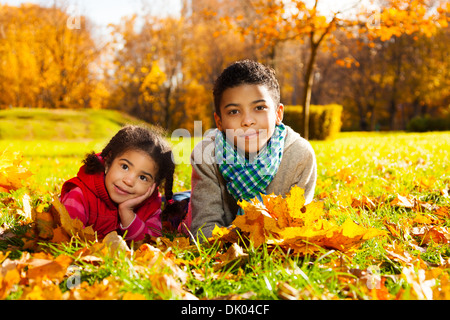 Felice bambina e suo fratello che stabilisce nel prato nel parco Foto Stock