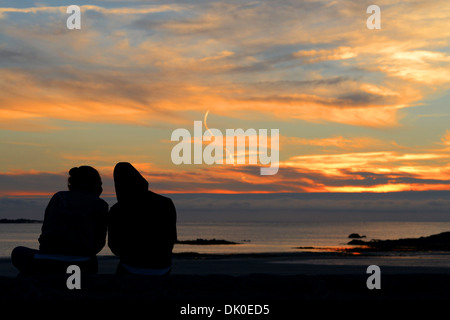 Una giovane coppia guardare il tramonto sopra l'isola di Guernsey Foto Stock