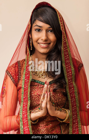 Ritratto di una bellissima donna indiana vestito in abiti tradizionali tenendo le mani in Namaste gesto. Foto Stock