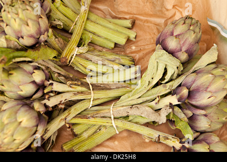 Chiudere fino ad alto angolo di visione da direttamente al di sopra del legato organico grappoli di carciofo al mercato agricolo Foto Stock