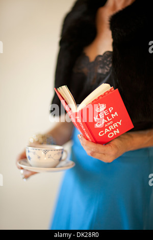 Vicino la sezione mediana di ben vestito donna holding tazzina e la lettura di " mantenere la calma e a portare sul' prenota Foto Stock