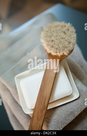 Angolo di Alta Vista della spazzola scrub sulla sommità del sapone e pila di asciugamani in spa Foto Stock