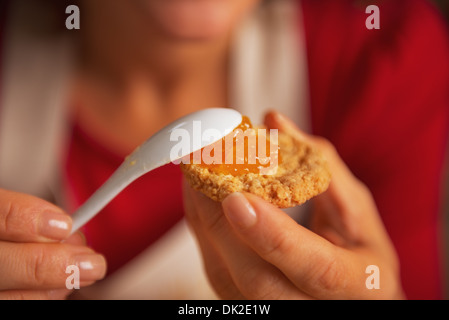 Primo piano sul giovane donna mettendo orange jam su cookie Foto Stock