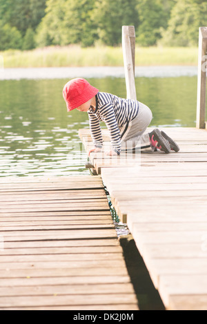 Stile di vita momento di estate infanzia. Bambina gioca su jetty, Svezia Foto Stock