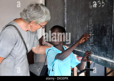 Black Boy e insegnante di bianco in una classe di una scuola di volontariato gestiti dalla Chiesa cattolica. Accra, Africa occidentale Foto Stock