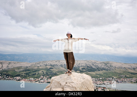 Ritratto di sorridere metà donna adulta con le braccia tese in piedi sulla roccia, Isola di Pag, Croazia, Europa Foto Stock