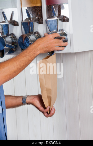 Maschio di acquisto del cliente i chicchi di caffè dal distributore automatico Foto Stock