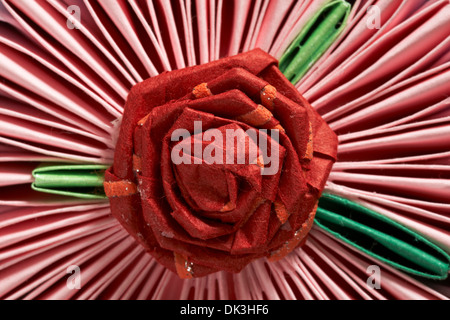 Origami - guardando verso il basso sulla parte superiore della tortina con dettaglio di Red Rose fiore Foto Stock