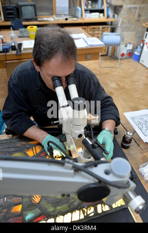 Erfurt, Germania. 27 Nov, 2013. Thomas Vetro, vetraio e restauratore nel laboratorio di vetro della Cattedrale di Erfurt, guarda un costruito fuori della finestra della Cattedrale attraverso un microscopio a Erfurt, Germania, 27 novembre 2013. Il restauro della Cattedrale di una finestra che è costituita da un centinaio di riquadri singolo dura circa due anni. Le finestre sono state realizzate negli anni tra il 1380 e il 1420. Foto: Marc Tirl/ZB/dpa/Alamy Live News Foto Stock