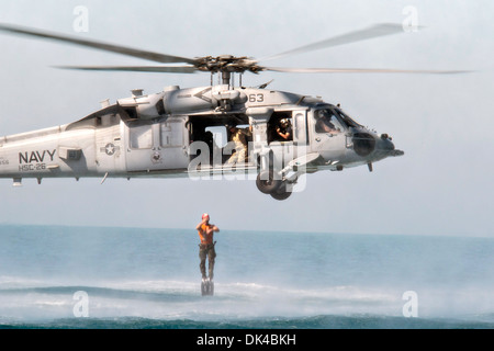 US Navy velisti assegnati al comandante, gruppo di attività 56.1 e marinai della Royal Bahraini Forze Navali condurre una miniera pouncer operazione da un MH-60s Seahawk elicottero durante l'esercizio risposta al Neon 24 ottobre 2013 nel Mare Arabico. Risposta al neon è un accordo bilaterale, l'eliminazione degli ordigni esplosivi e immersioni subacquee impegno TRA STATI UNITI Navy e Regno del Bahrein Forze di difesa. Foto Stock