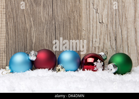 Decorazione di natale con sfondo di legno, neve baubles di Natale verde, blu e rosso Foto Stock