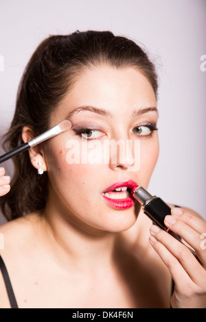 Giovane donna si applica eye shadow e il rossetto Foto Stock