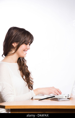 Giovane donna alla scrivania con computer e caffè su sfondo bianco Foto Stock