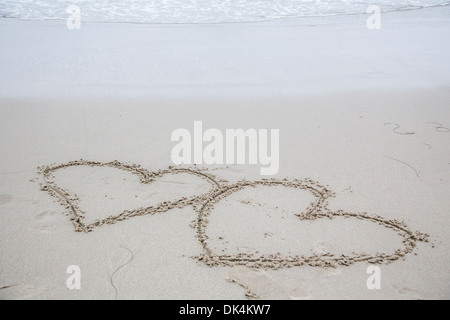Due cuori scavata nella sabbia bagnata Foto Stock