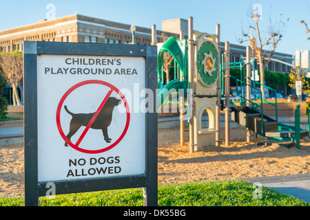 Segno che vieta i cani in corrispondenza di una zona giochi per bambini. Foto Stock