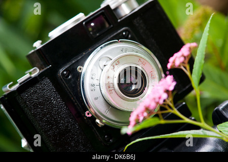 Primo piano di un classico russo fatto SLR fotocamera a pellicola noto come Cmena vicino a fiore. Foto Stock