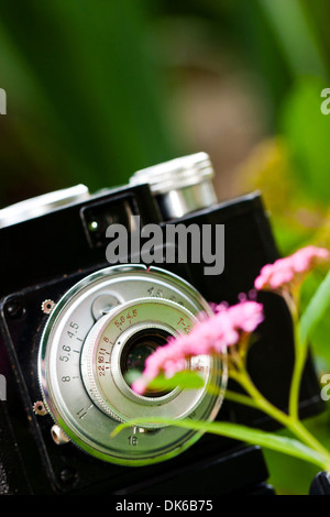 Primo piano di un classico russo fatto SLR fotocamera a pellicola noto come Cmena vicino a fiore. Foto Stock