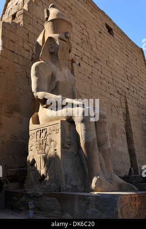 Seduto Statua di Ramesse II e il primo pilone in entrata al Tempio di Luxor - Luxor, Egitto Foto Stock