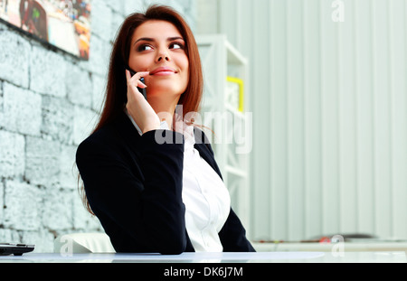 Giovane imprenditrice felice di parlare al telefono e guardando lontano a copyspace in office Foto Stock