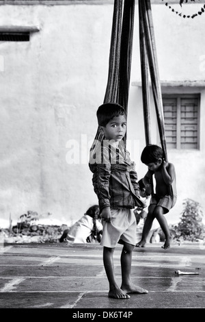 Giovani indiani ragazzi giocare su sari altalene a casa in un ambiente rurale villaggio indiano. Andhra Pradesh, India. In bianco e nero. Foto Stock