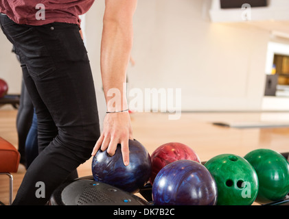 Giovane uomo scegliendo palla da bowling dalla cremagliera Foto Stock