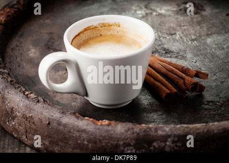 Tazza da caffè con bastoncini di cannella su sfondo scuro Foto Stock