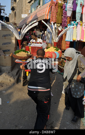 I giovani uomini locali spingono e tirano un carrello alimentare attraverso un mercato nel quartiere islamico della capitale egiziana il Cairo. Foto Stock